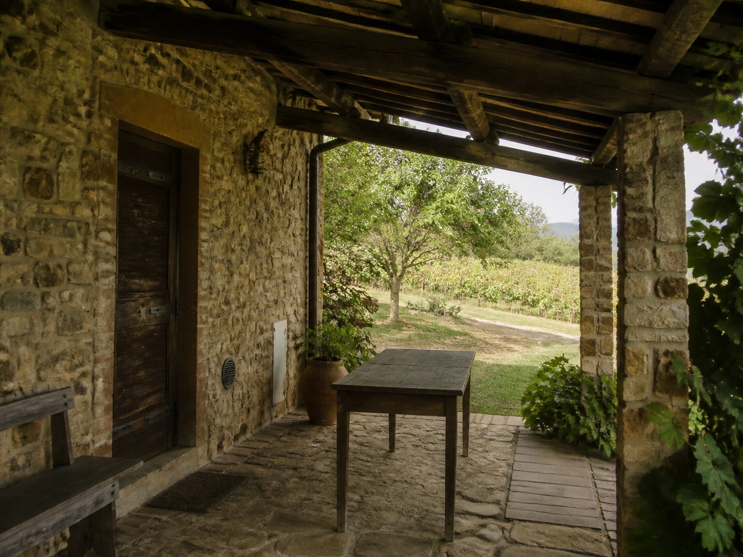 Portico in pietra e legno con tavolo rustico affacciato sui vigneti