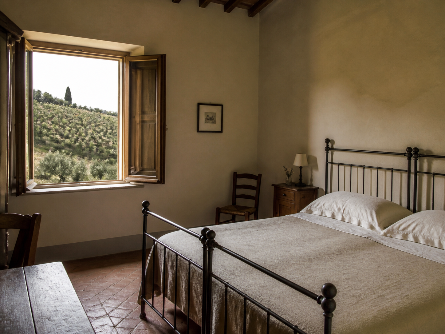 Camera con letto in ferro battuto e finestra aperta sulla collina vitata